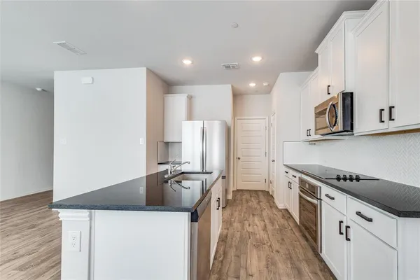 a kitchen with stainless steel appliances a refrigerator a stove and white cabinets