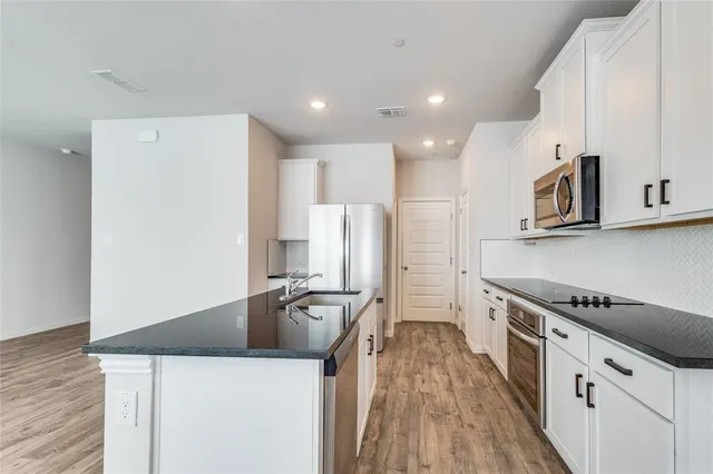a kitchen with stainless steel appliances a refrigerator a stove and white cabinets