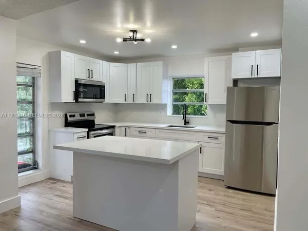 a kitchen with kitchen island a sink stainless steel appliances and cabinets