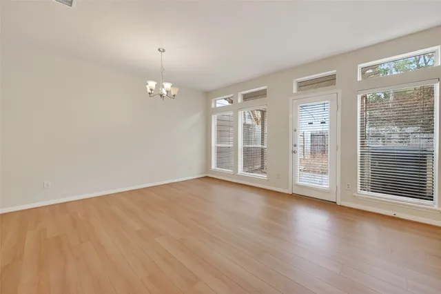 a view of a livingroom with a chandelier fan front door and wooden floor