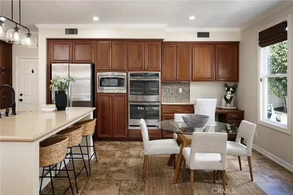 a kitchen with stainless steel appliances wooden cabinets dining table and chairs
