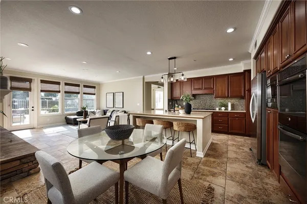 a kitchen with a dining table chairs stainless steel appliances and cabinets