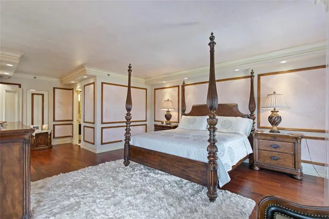 a bedroom with a bed a mirror on dresser and a large window
