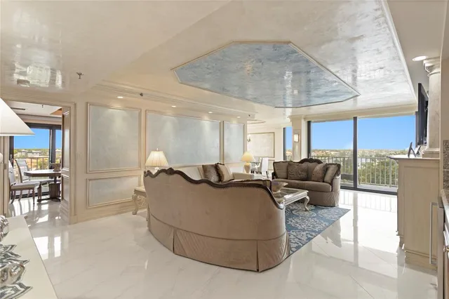 a living room with furniture a chandelier and kitchen view
