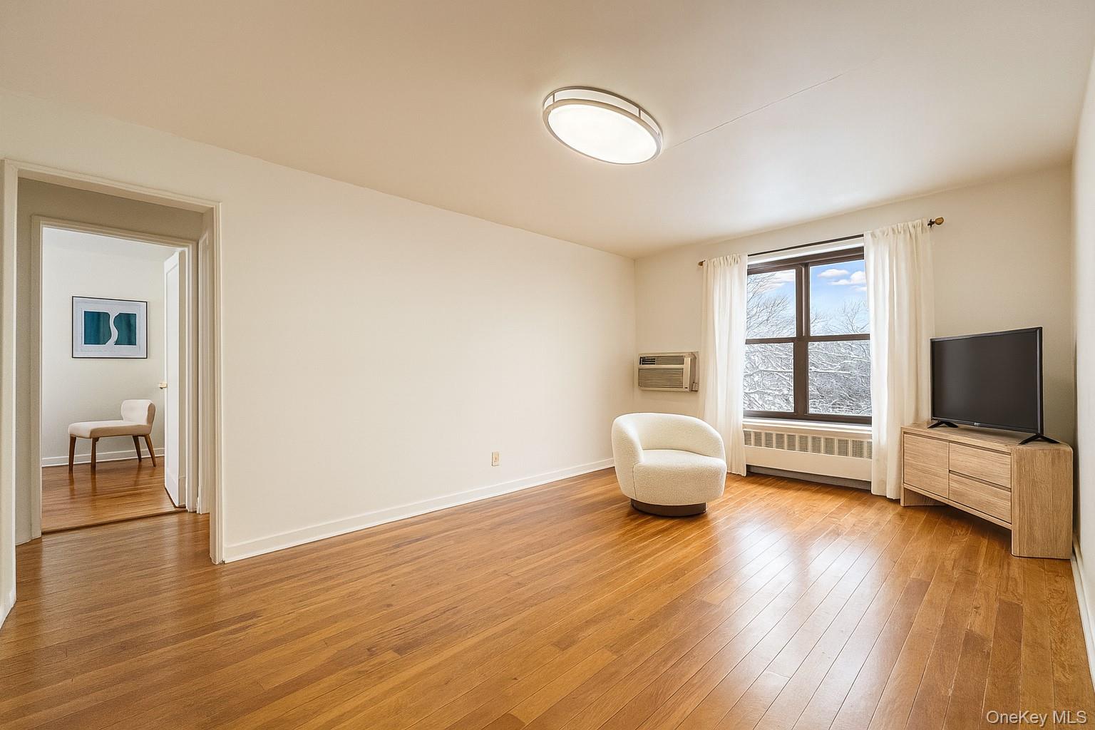 7 Terrace Circle, Unit 3D Great Neck, NY 11021 - Photo 2 of 31 a bedroom with furniture and a flat screen tv