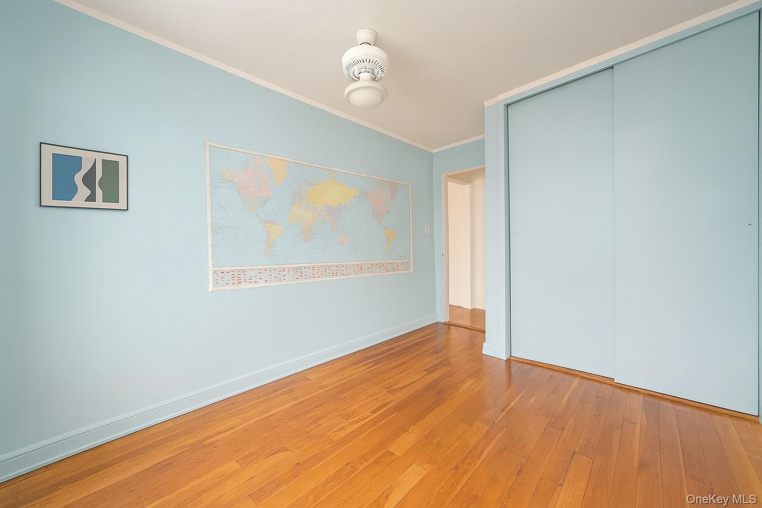 7 Terrace Circle, Unit 3D Great Neck, NY 11021 - Photo 9 of 31 an empty room with wooden floor ceiling fan and windows