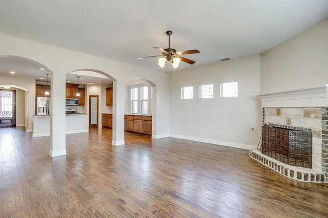 an empty room with wooden floor fireplace and windows