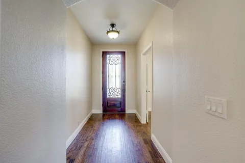 a view of hallway with a window and wooden floor