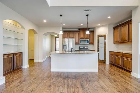 a large kitchen with cabinets wooden floor and stainless steel appliances