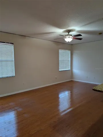 a view of an empty room with wooden floor and a window