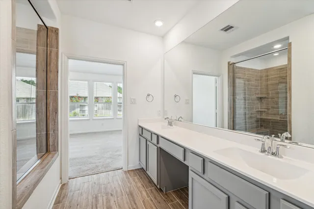 a spacious bathroom with a double vanity sink a mirror and a shower