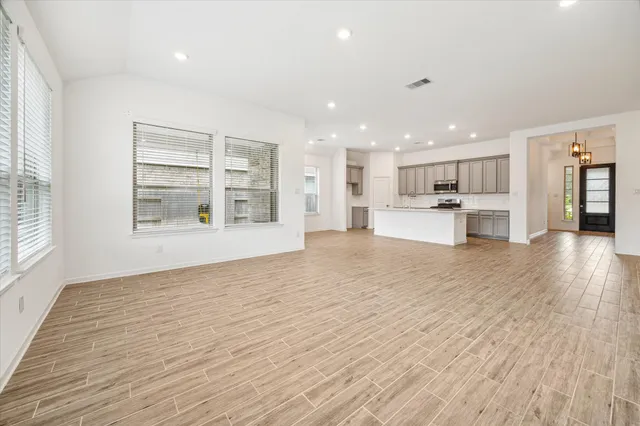 a view of a kitchen with kitchen island a sink wooden floor and a refrigerator