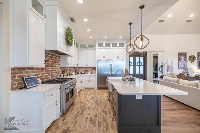 a large kitchen with stainless steel appliances granite countertop a sink a stove and a wooden floors