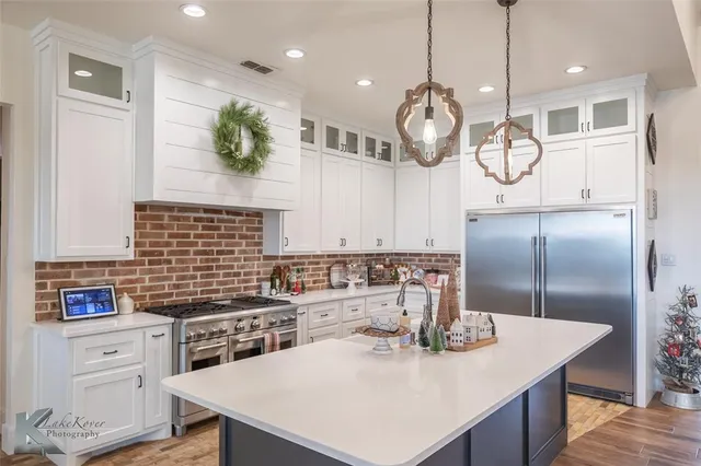 a kitchen with kitchen island a counter space a sink appliances and cabinets