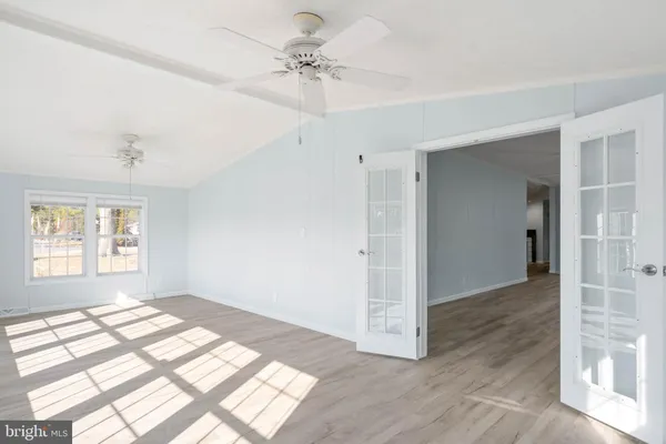 a view of an empty room with a window and wooden floor