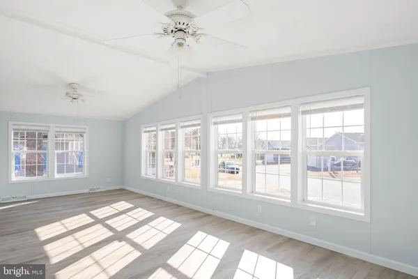a view of an empty room with wooden floor and window