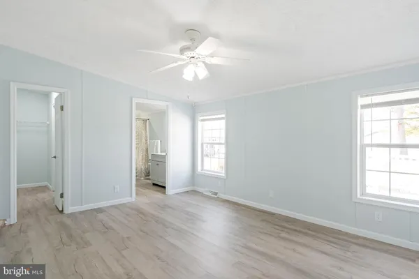 an empty room with wooden floor and fan