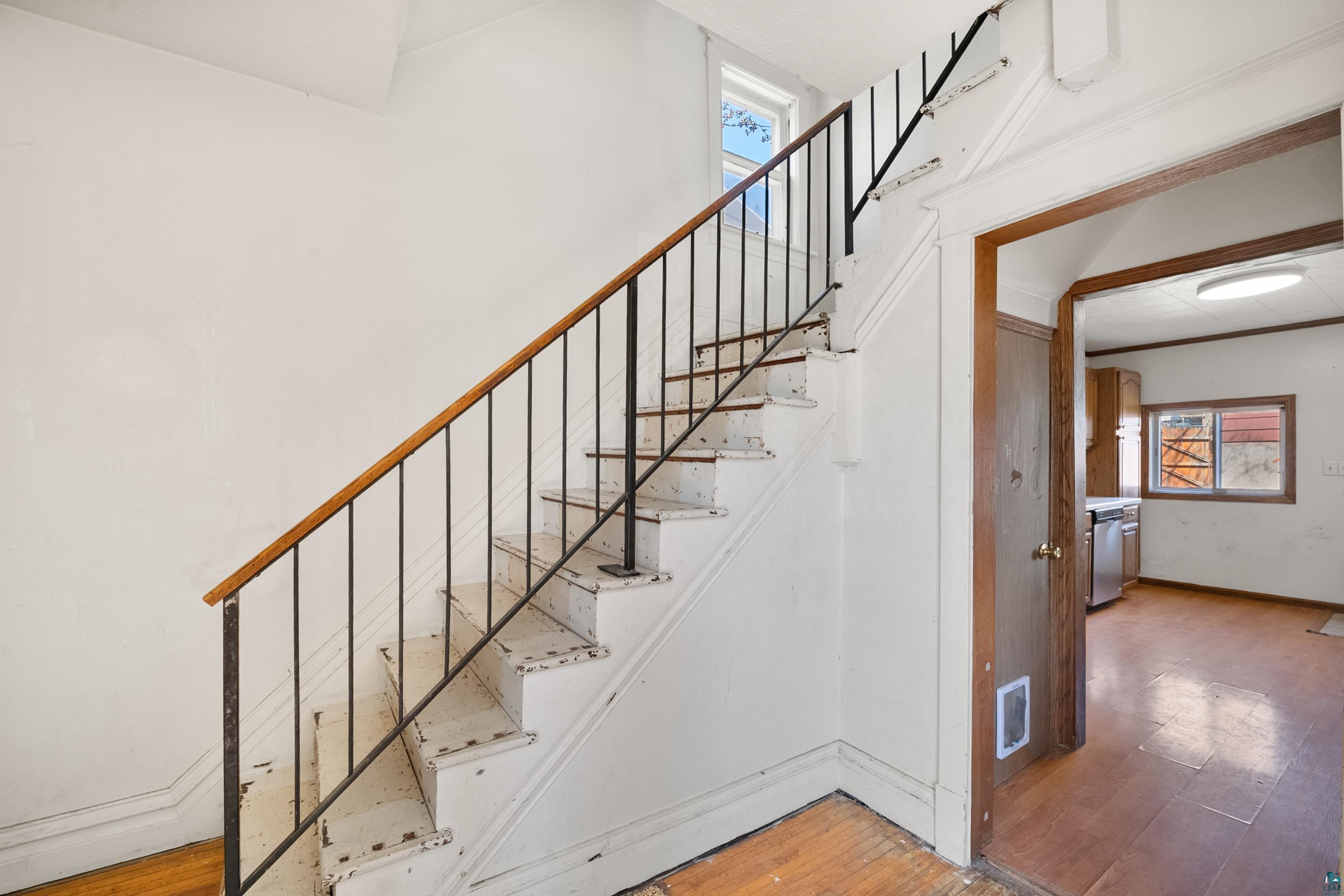 3067 Restormel Street Duluth, MN 55806 - Photo 9 of 25 Staircase with wood handrail, black metal balusters, and white risers