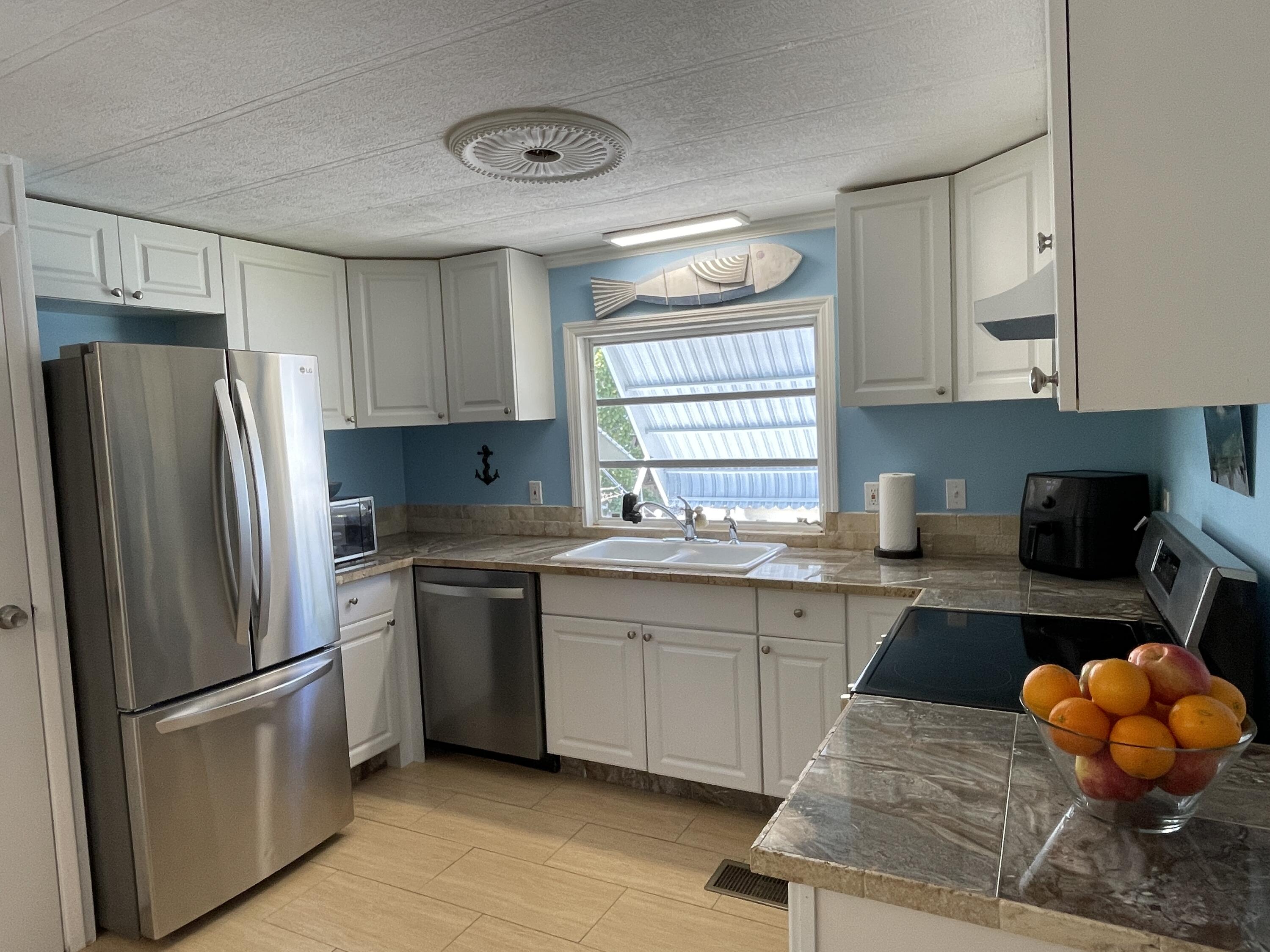 27853 Coral Shores Road Summerland Key, FL 33042 - Photo 16 of 47 a kitchen with stainless steel appliances granite countertop a refrigerator sink stove microwave and cabinets