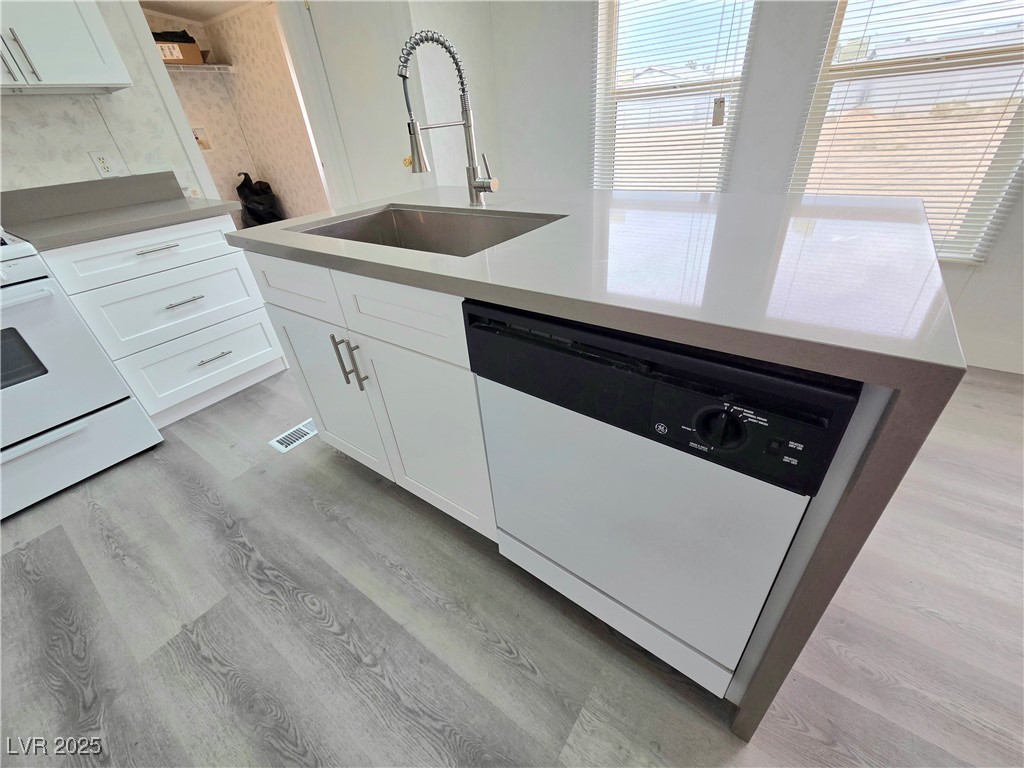 3290 Medicine Man Road Pahrump, NV 89048 - Photo 11 of 27 Kitchen with white appliances, white cabinetry, light wood finished floors, an island with sink, and light stone countertops