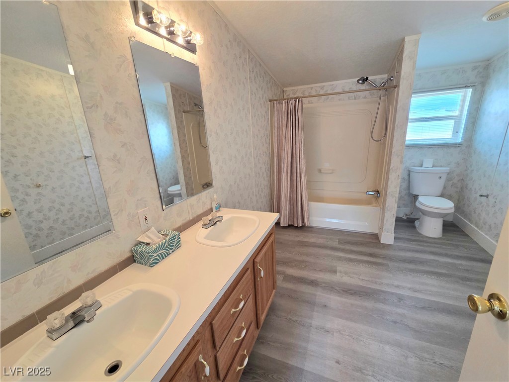 3290 Medicine Man Road Pahrump, NV 89048 - Photo 16 of 27 Bathroom with shower / bathtub combination with curtain, double vanity, wallpapered walls, and dark wood-type flooring