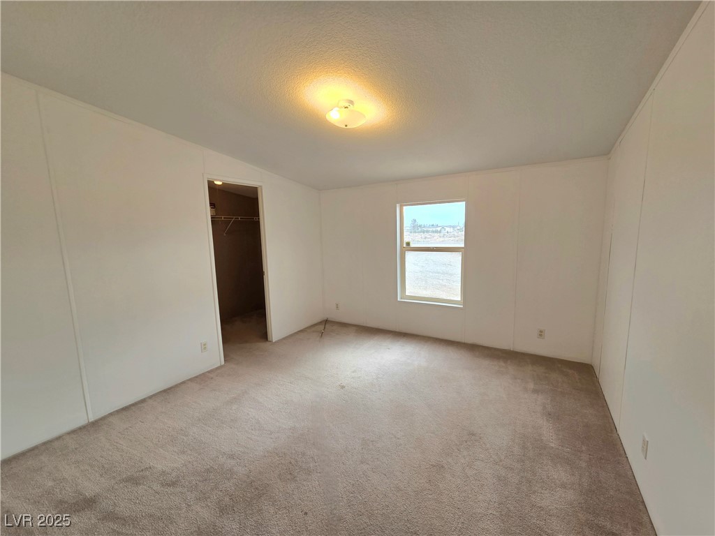 3290 Medicine Man Road Pahrump, NV 89048 - Photo 18 of 27 Carpeted spare room with a decorative wall and a textured ceiling