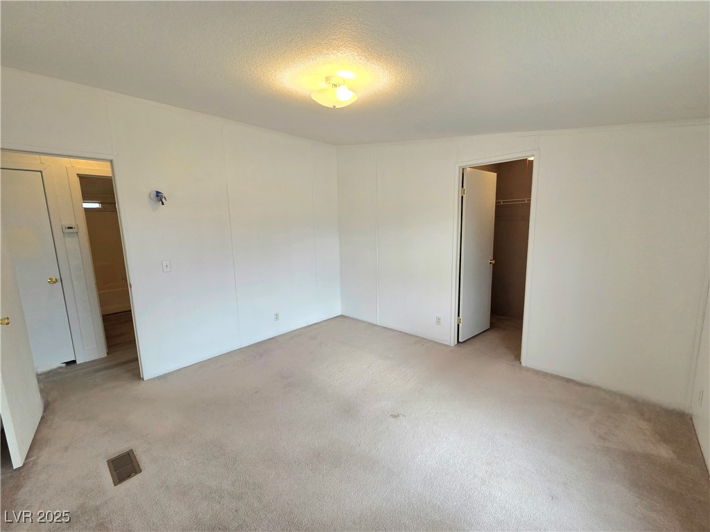 3290 Medicine Man Road Pahrump, NV 89048 - Photo 19 of 27 Unfurnished bedroom with a spacious closet, light carpet, and a textured ceiling