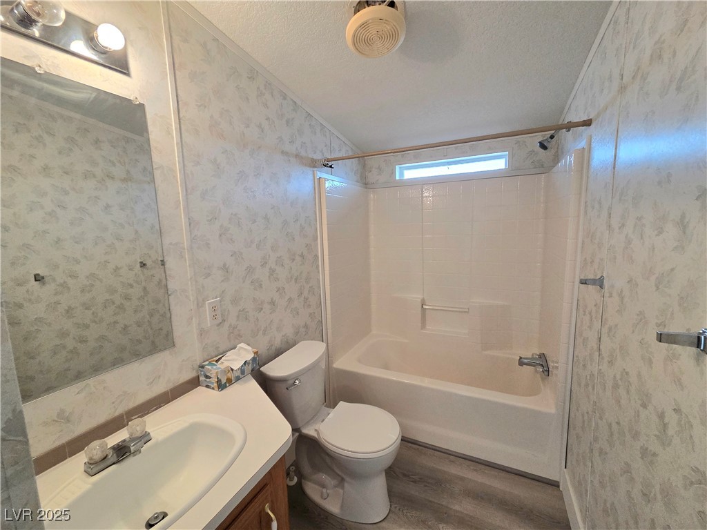 3290 Medicine Man Road Pahrump, NV 89048 - Photo 21 of 27 Full bathroom with wallpapered walls, shower / tub combination, a textured ceiling, vanity, and dark wood finished floors