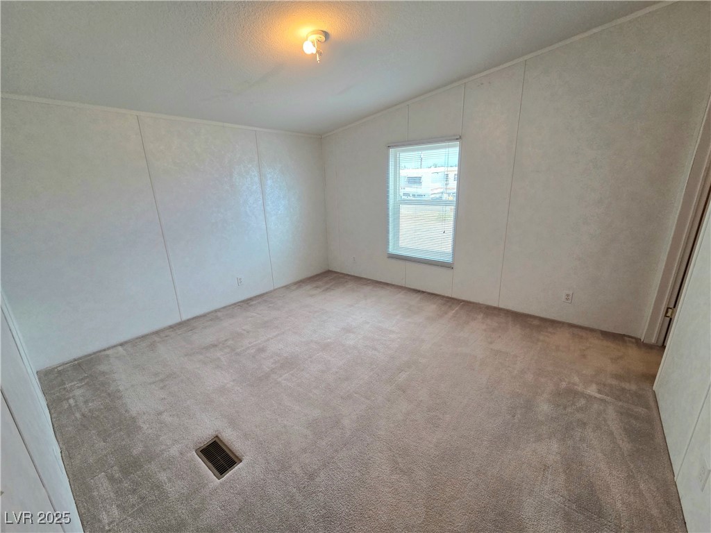 3290 Medicine Man Road Pahrump, NV 89048 - Photo 22 of 27 Unfurnished room featuring carpet floors, a decorative wall, a textured ceiling, and lofted ceiling