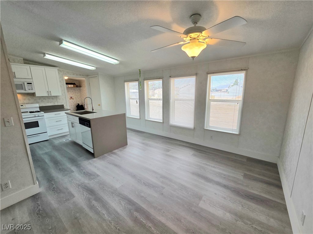3290 Medicine Man Road Pahrump, NV 89048 - Photo 7 of 27 Kitchen with white cabinetry, light wood-style flooring, white appliances, an island with sink, and ceiling fan