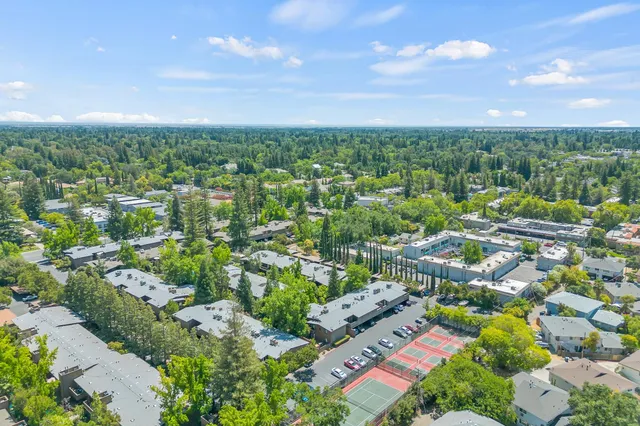 an aerial view of residential houses with outdoor space and trees