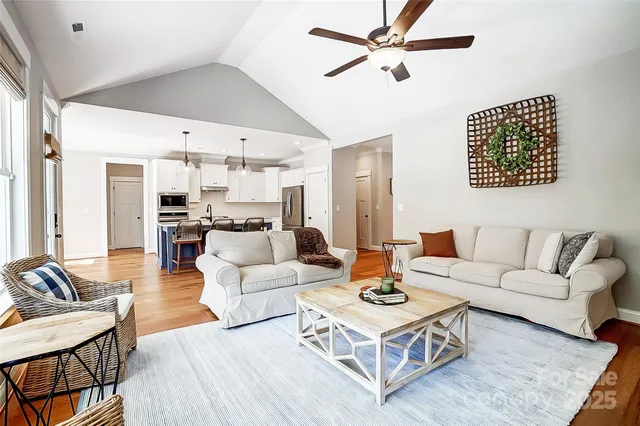 a living room with furniture kitchen view and a chandelier