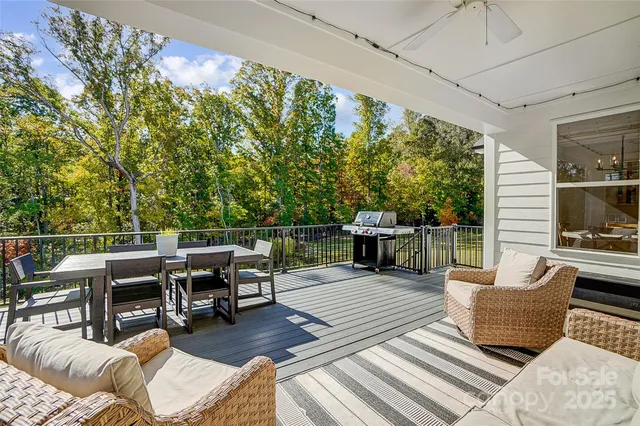 a roof deck with table and chairs couches with wooden floor and fence