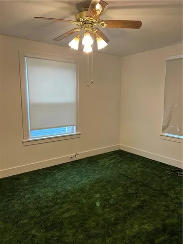 a view of an empty room with window and chandelier fan