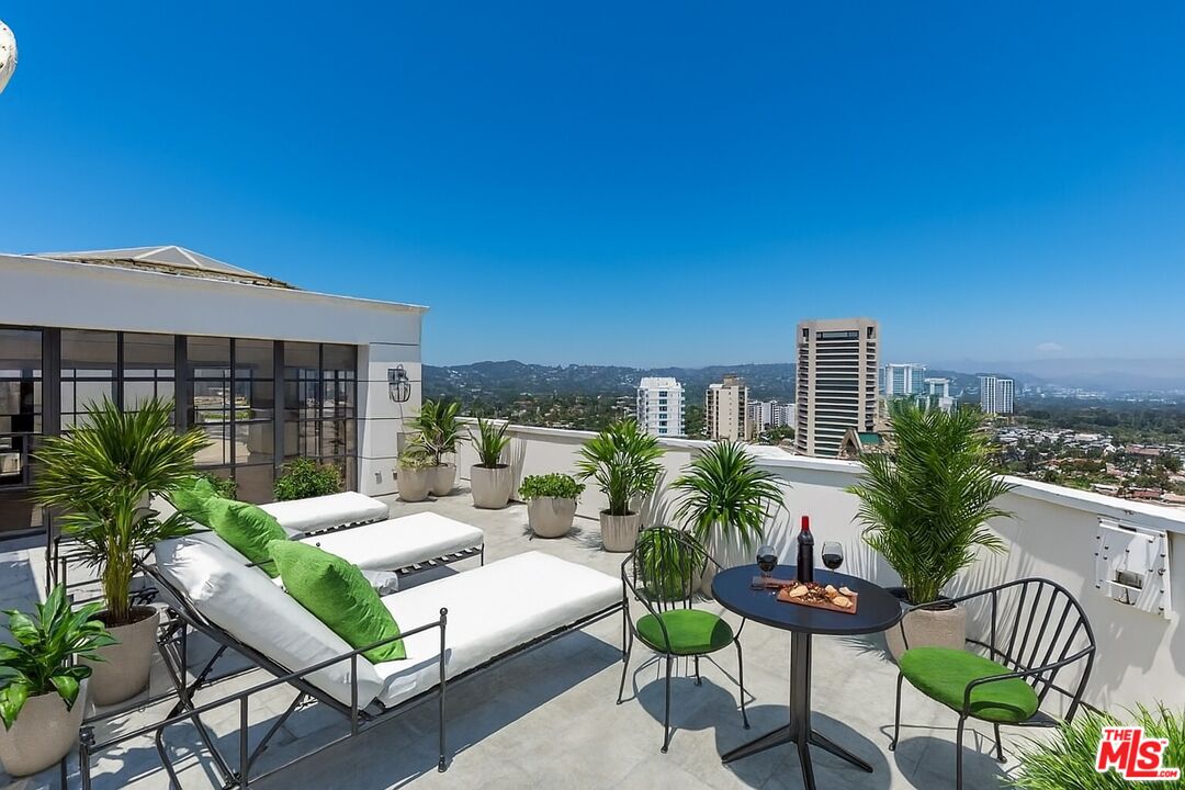 10601 Wilshire Boulevard, Unit PH E Los Angeles, CA 90024 - Photo 9 of 10 a view of a patio with couches table and chairs under an umbrella with potted plants