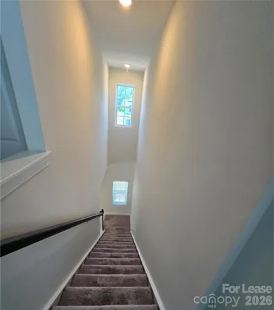 a view of a hallway with wooden floor and a bathroom