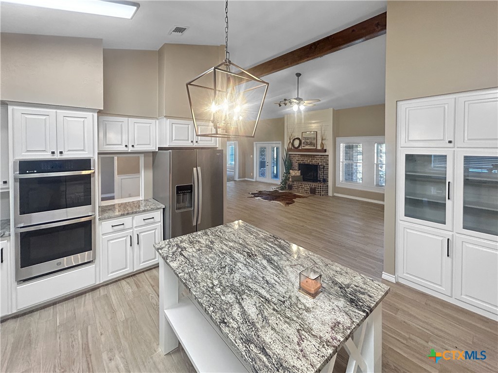 2776 South Highway 77 Cameron, TX 76520 - Photo 8 of 30 a kitchen with stainless steel appliances granite countertop a refrigerator oven stove a island and white cabinets with wooden floors
