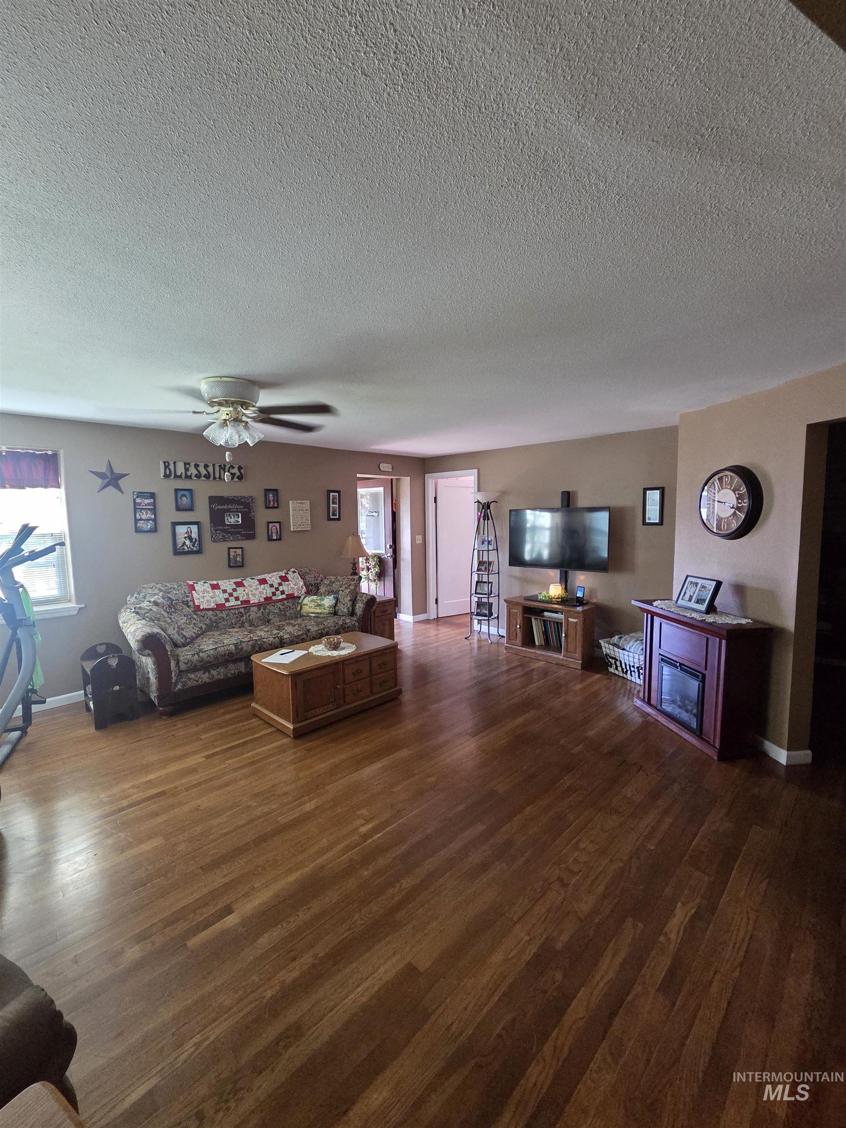 109 South 3rd Street Pomeroy, WA 99347 - Photo 6 of 36 Spacious living area featuring rich wood-finish flooring, neutral wall tones, and a ceiling fan with integrated lighting