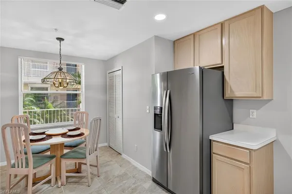 a kitchen with stainless steel appliances a refrigerator a table and chairs in it
