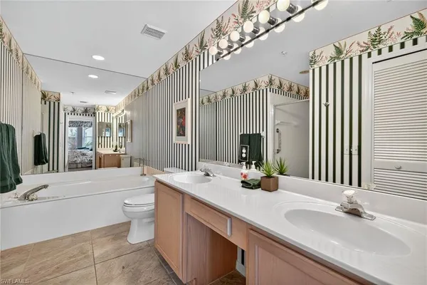 a bathroom with a double vanity sink a toilet and a large mirror