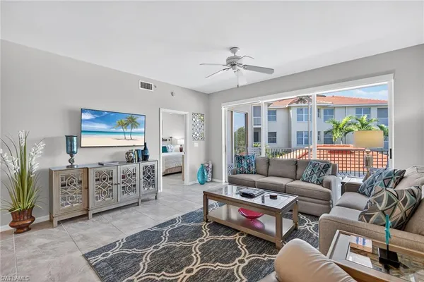 a living room with furniture a flat screen tv and a floor to ceiling window