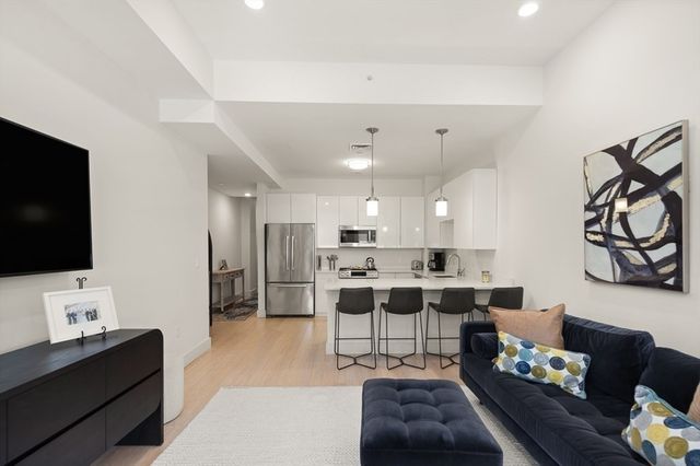 a living room with furniture a flat screen tv and kitchen view