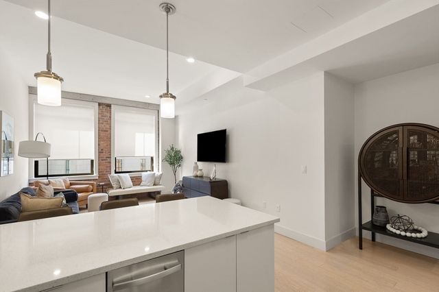 a living room with furniture a flat screen tv and a view of kitchen
