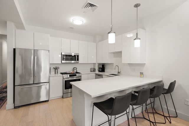 a kitchen with stainless steel appliances granite countertop a refrigerator a sink a stove a dining table and chairs