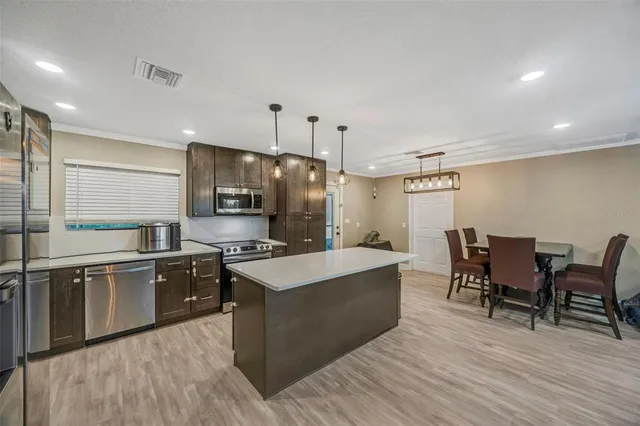 a large kitchen with stainless steel appliances a stove a sink a oven a dining table and chairs