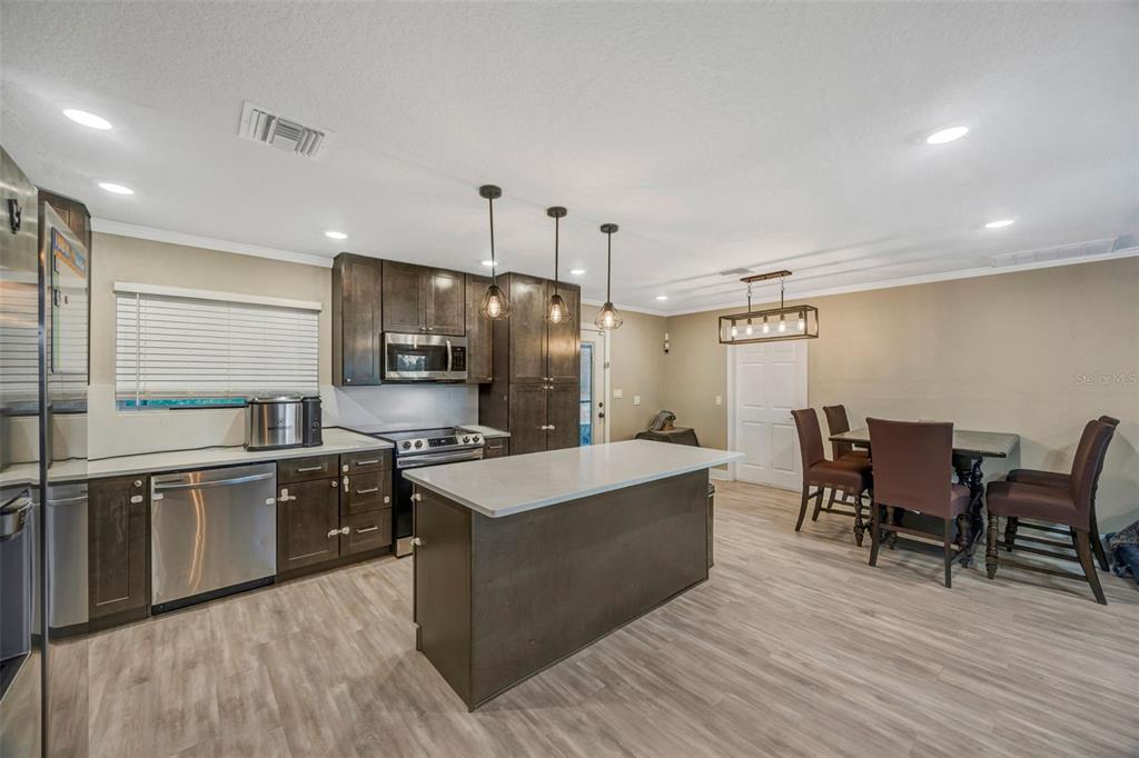 7149 Spruce Drive Weeki Wachee, FL 34607 - Photo 3 of 23 a large kitchen with stainless steel appliances a stove a sink a oven a dining table and chairs