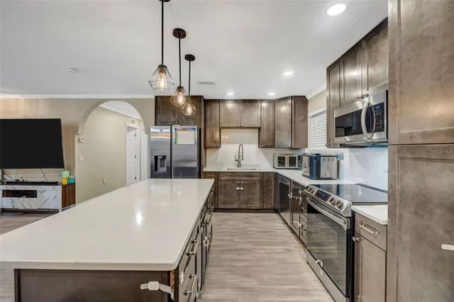 a large kitchen with stainless steel appliances kitchen island granite countertop a large stove a refrigerator a oven a island with wooden floor and cabinets