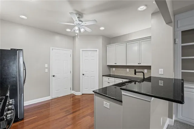 a kitchen with granite countertop a refrigerator a sink dishwasher and wooden cabinets with wooden floor