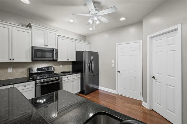 a kitchen with granite countertop a stove cabinets and stainless steel appliances