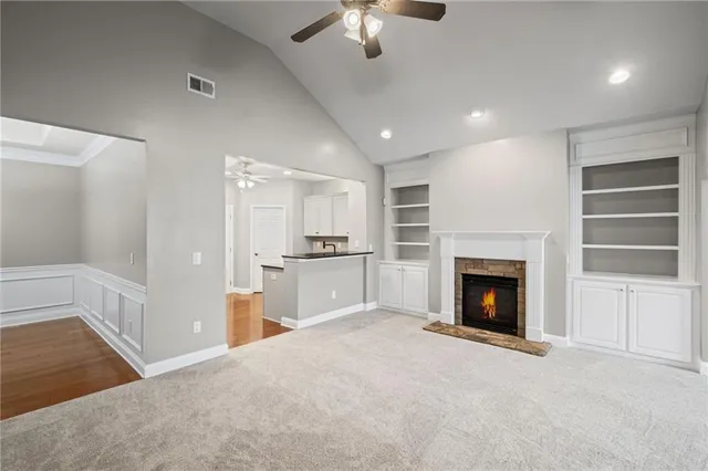 a view of a livingroom with a fireplace a ceiling fan and windows